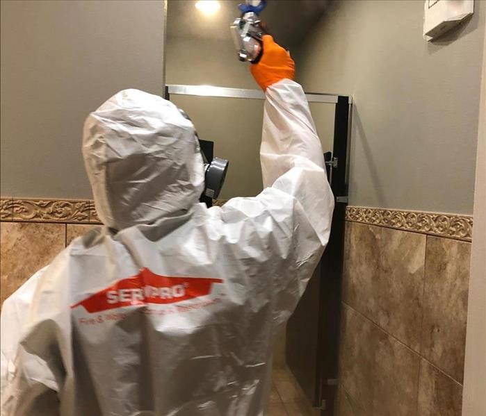 man in personal protective equipment cleaning bathroom tile 