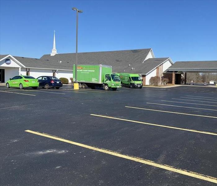 Exterior of a local church with bright green SERVPRO trucks parked in front of the building