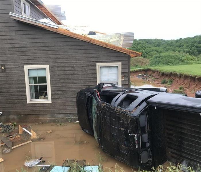 tornado damaged home with vehicle flipped over in front of home 